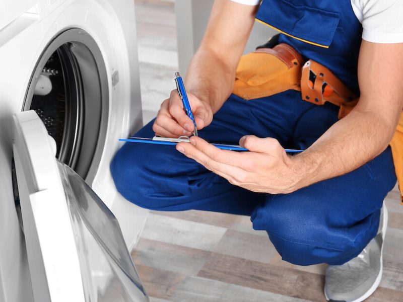 Plumber with clipboard near washing machine Plumber with clipboard near washing machine